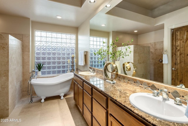 bathroom featuring double vanity, a freestanding tub, recessed lighting, and a sink