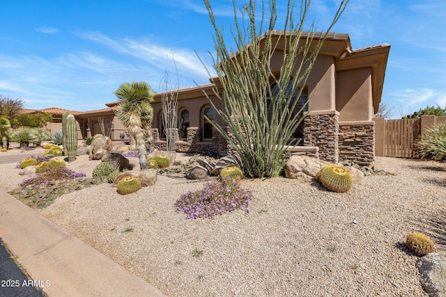 view of front of property with fence, stone siding, and stucco siding