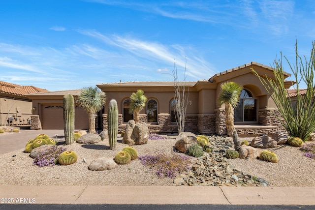 view of front of property with stucco siding, stone siding, driveway, and an attached garage