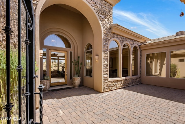 doorway to property with stone siding, stucco siding, and a patio