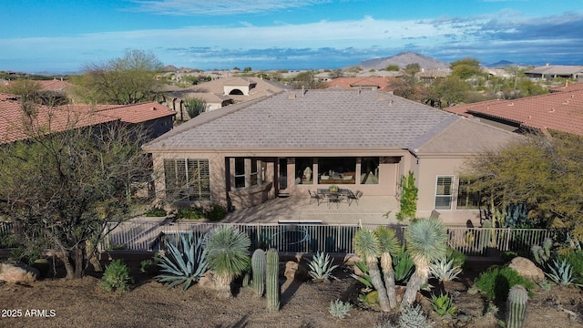 back of property with a patio, fence, a shingled roof, stucco siding, and a mountain view