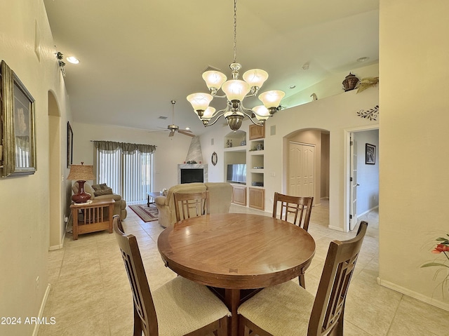 tiled dining space with a fireplace, ceiling fan with notable chandelier, built in features, and vaulted ceiling