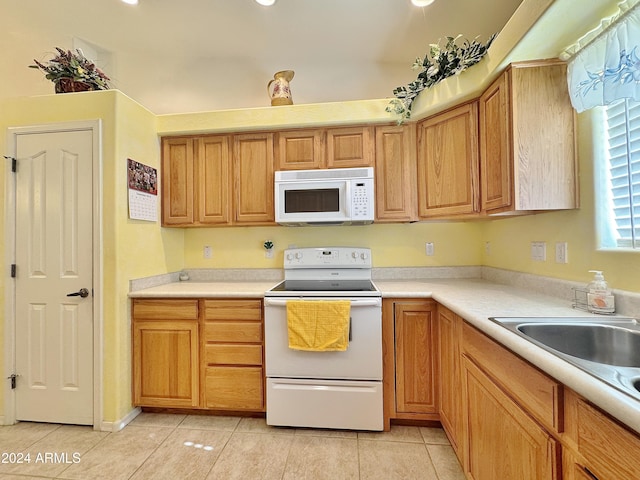 kitchen featuring white appliances, sink, and light tile patterned floors