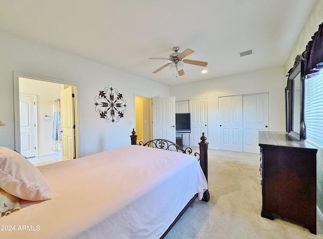 bedroom featuring light carpet, two closets, ceiling fan, and ensuite bathroom