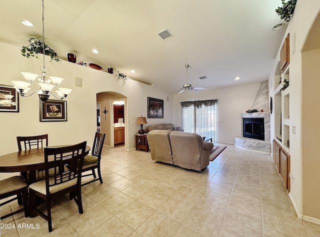 dining space with ceiling fan with notable chandelier, a large fireplace, and light tile patterned flooring