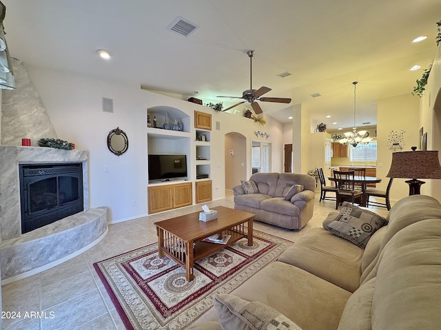 living room with light tile patterned flooring, ceiling fan with notable chandelier, built in features, and a premium fireplace