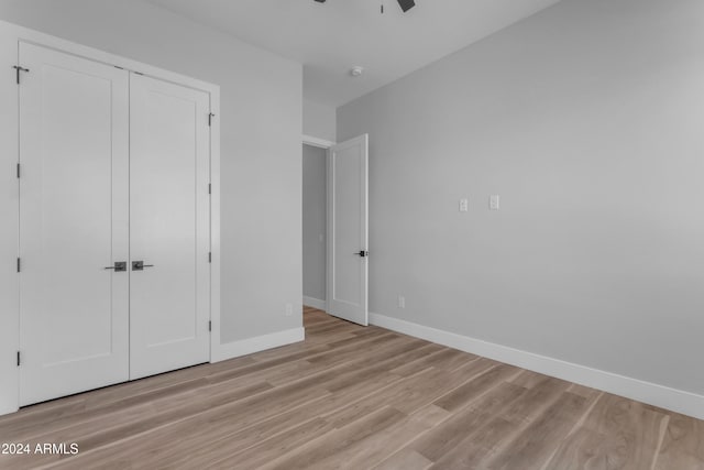 unfurnished bedroom featuring ceiling fan, a closet, and light hardwood / wood-style flooring