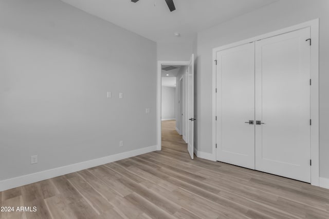 unfurnished bedroom with light wood-type flooring, ceiling fan, and a closet