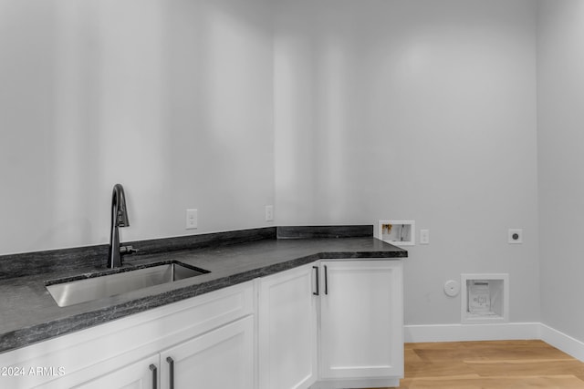 kitchen featuring white cabinets, light hardwood / wood-style floors, dark stone counters, and sink