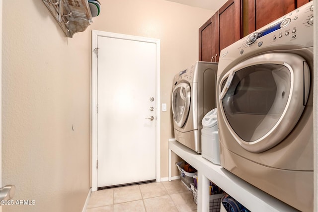 laundry room with cabinets, washing machine and dryer, and light tile patterned flooring