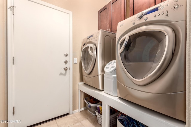 clothes washing area featuring cabinets, light tile patterned floors, and separate washer and dryer