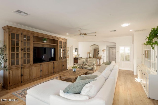 living room with ceiling fan, light wood-type flooring, and crown molding