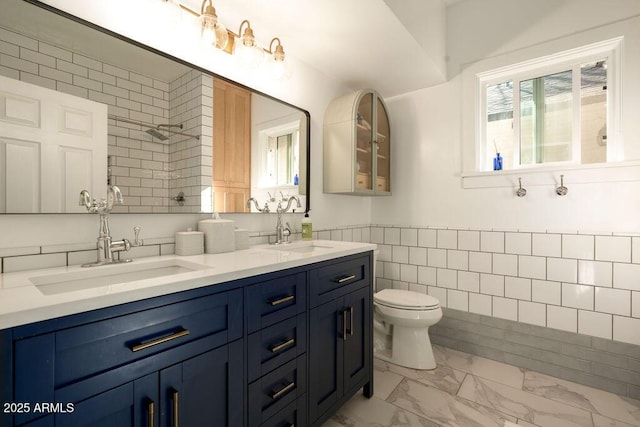 bathroom featuring toilet, vanity, and tile walls