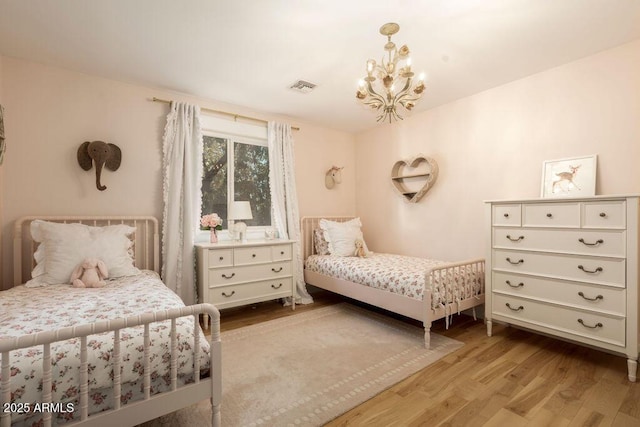 bedroom with light wood-type flooring and an inviting chandelier