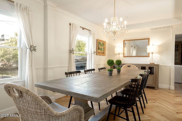 dining area featuring a notable chandelier, crown molding, and light parquet floors