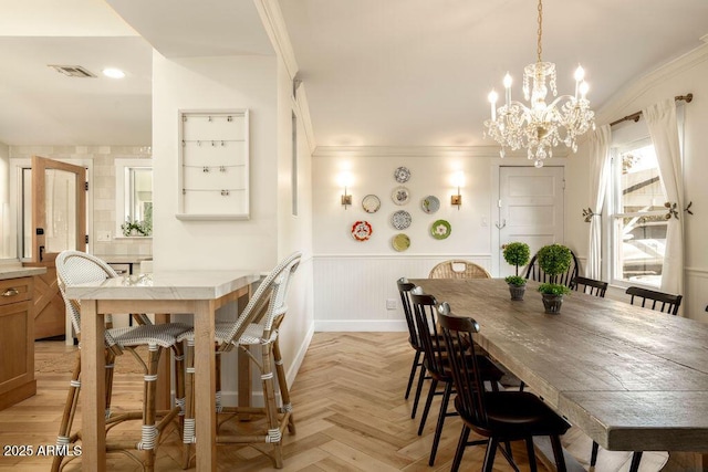 dining room featuring an inviting chandelier, crown molding, and light parquet flooring