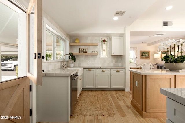 kitchen with stainless steel dishwasher, light hardwood / wood-style flooring, lofted ceiling, backsplash, and sink