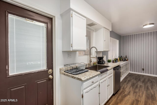 kitchen featuring a sink, baseboards, white cabinets, stainless steel dishwasher, and dark wood finished floors