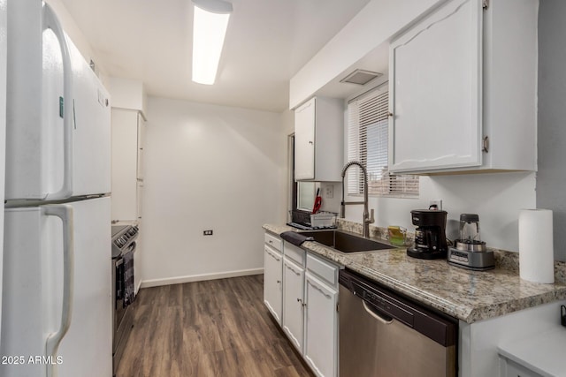 kitchen with dark wood-style floors, stainless steel appliances, white cabinets, a sink, and baseboards