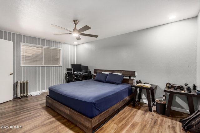 bedroom featuring radiator, ceiling fan, baseboards, and wood finished floors