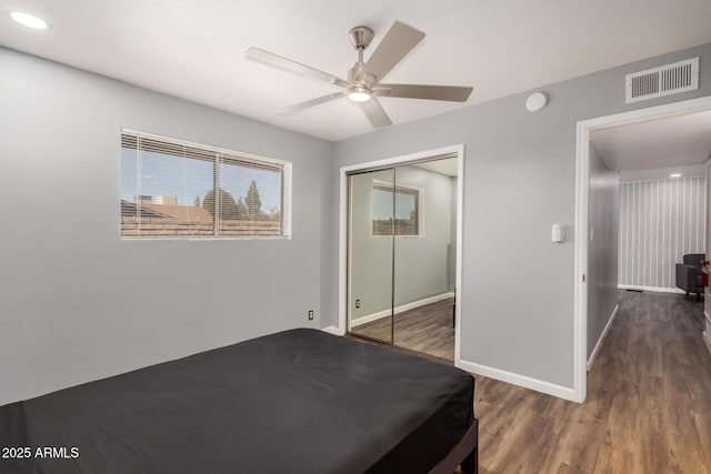 unfurnished bedroom featuring a closet, visible vents, a ceiling fan, wood finished floors, and baseboards