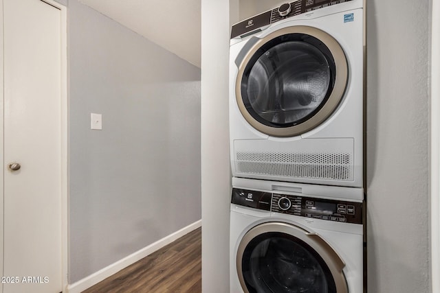 laundry area featuring laundry area, baseboards, stacked washing maching and dryer, and wood finished floors