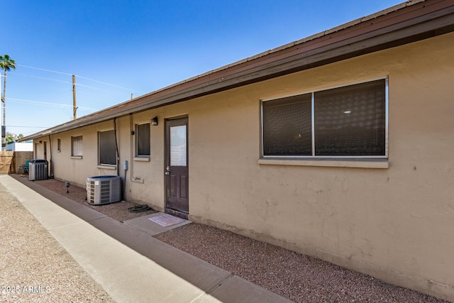 view of home's exterior with stucco siding, fence, and central air condition unit