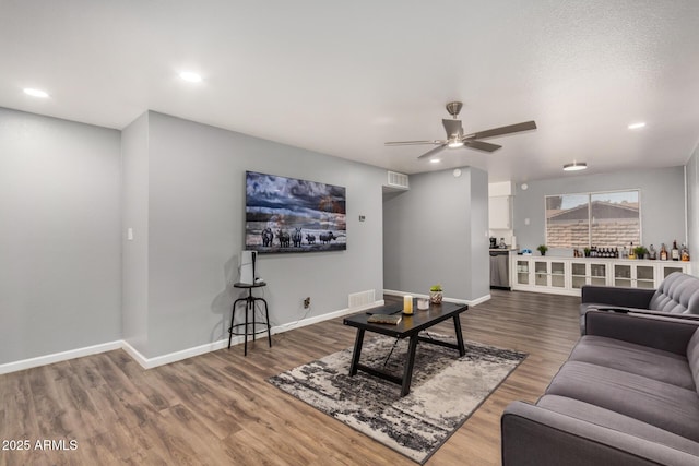 living room featuring ceiling fan, baseboards, and wood finished floors