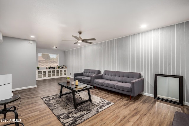 living area with ceiling fan, wood finished floors, and baseboards