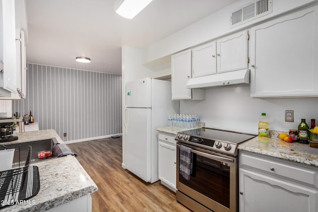 kitchen with electric stove, visible vents, light wood-style floors, freestanding refrigerator, and under cabinet range hood