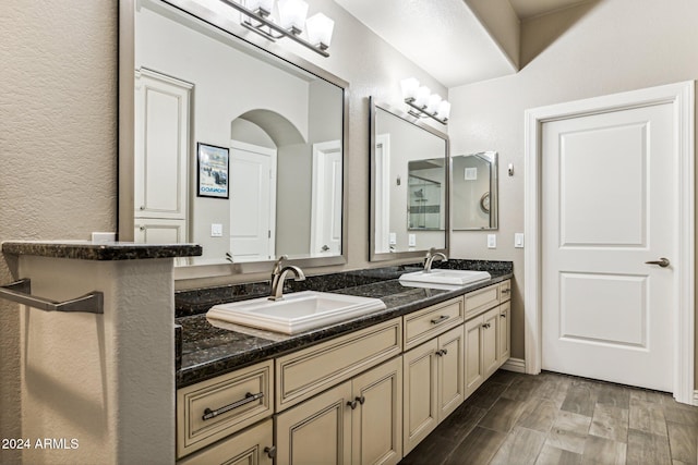 full bathroom with a textured wall, wood finished floors, a sink, and double vanity