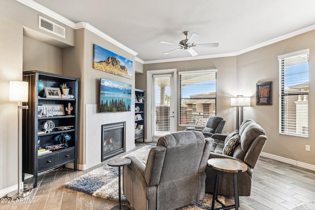 living area with baseboards, visible vents, wood finished floors, ceiling fan, and a tile fireplace