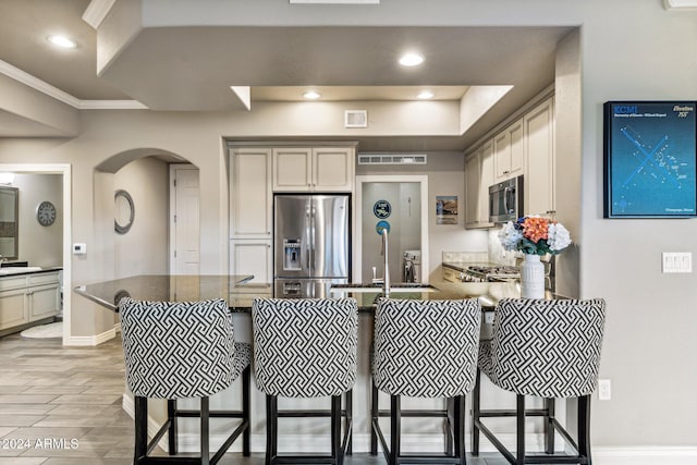 kitchen with stainless steel appliances, visible vents, a sink, arched walkways, and a peninsula