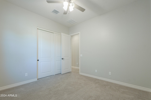 unfurnished bedroom featuring ceiling fan, light carpet, and a closet