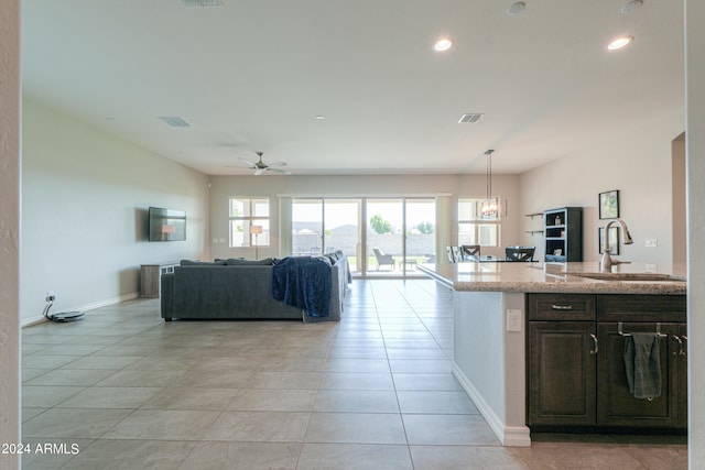 kitchen with dark brown cabinets, ceiling fan, light tile patterned floors, sink, and decorative light fixtures