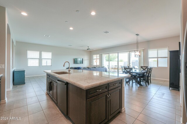 kitchen featuring light stone countertops, dishwasher, sink, light tile patterned flooring, and decorative light fixtures