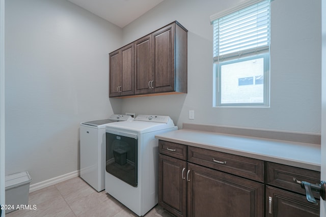 washroom featuring light tile patterned flooring, a wealth of natural light, cabinets, and washing machine and dryer