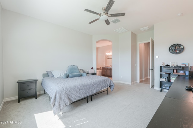 bedroom with ceiling fan, ensuite bath, and light carpet