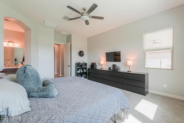 carpeted bedroom with ceiling fan and ensuite bath