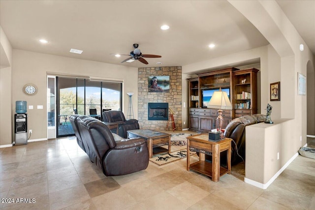 living room featuring ceiling fan, light tile flooring, and a fireplace