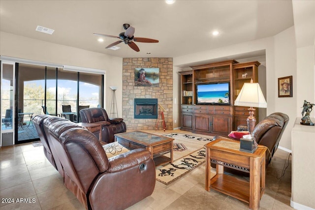 tiled living room with a stone fireplace and ceiling fan