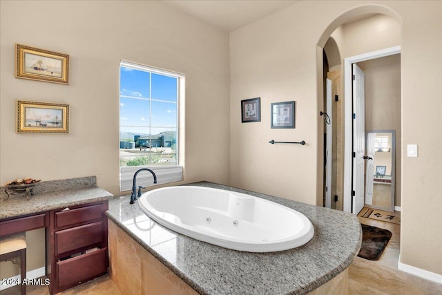 bathroom featuring tiled tub, vanity, and tile flooring