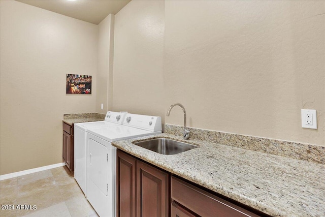 laundry room with washing machine and clothes dryer, cabinets, light tile flooring, and sink