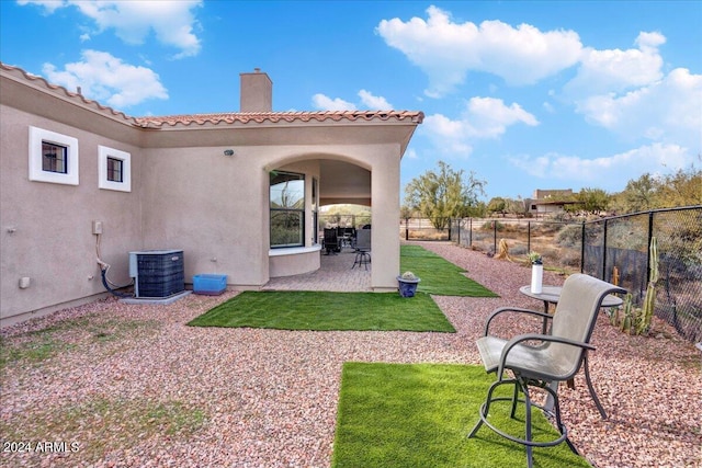 back of property with a lawn, central air condition unit, and a patio