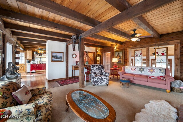 living room featuring hardwood / wood-style floors, wood walls, ceiling fan with notable chandelier, beamed ceiling, and wood ceiling