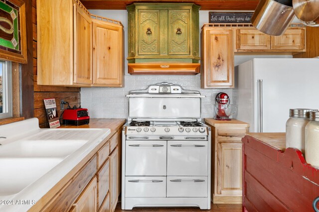 kitchen featuring light brown cabinets, sink, backsplash, white appliances, and custom exhaust hood