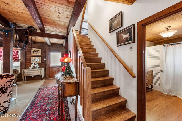 stairway with beamed ceiling, hardwood / wood-style floors, wooden walls, and wood ceiling