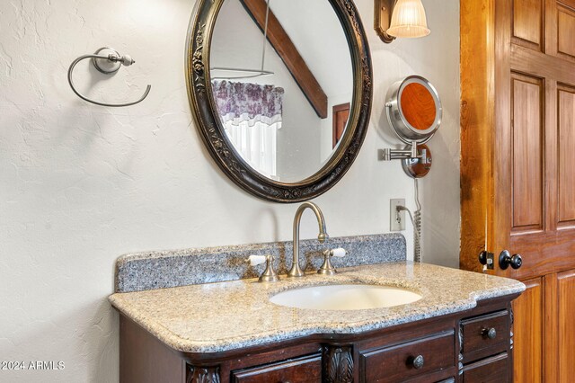 bathroom with beam ceiling and vanity