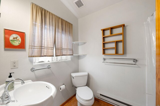 bathroom featuring vaulted ceiling, sink, wood-type flooring, a baseboard radiator, and toilet