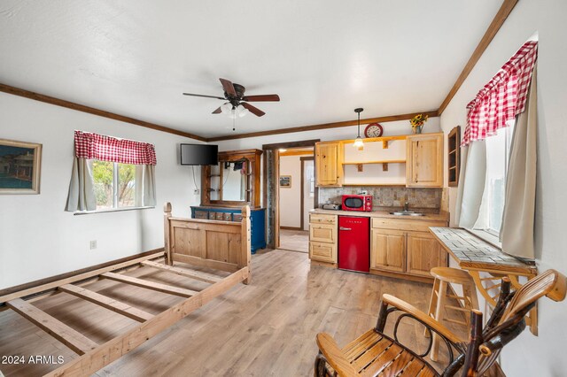 kitchen with pendant lighting, backsplash, sink, light wood-type flooring, and ornamental molding